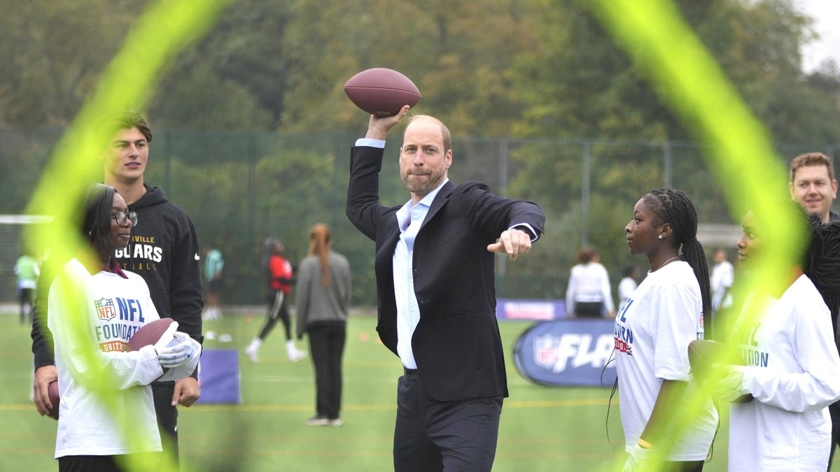 Prince William, Prince of Wales throws a football at a target, watched by Louis Rees-Zammit (L) as he attends a NFL Foundation NFL Flag event, an inclusive and fast paced American Football format on October 15, 2024 in London, England.