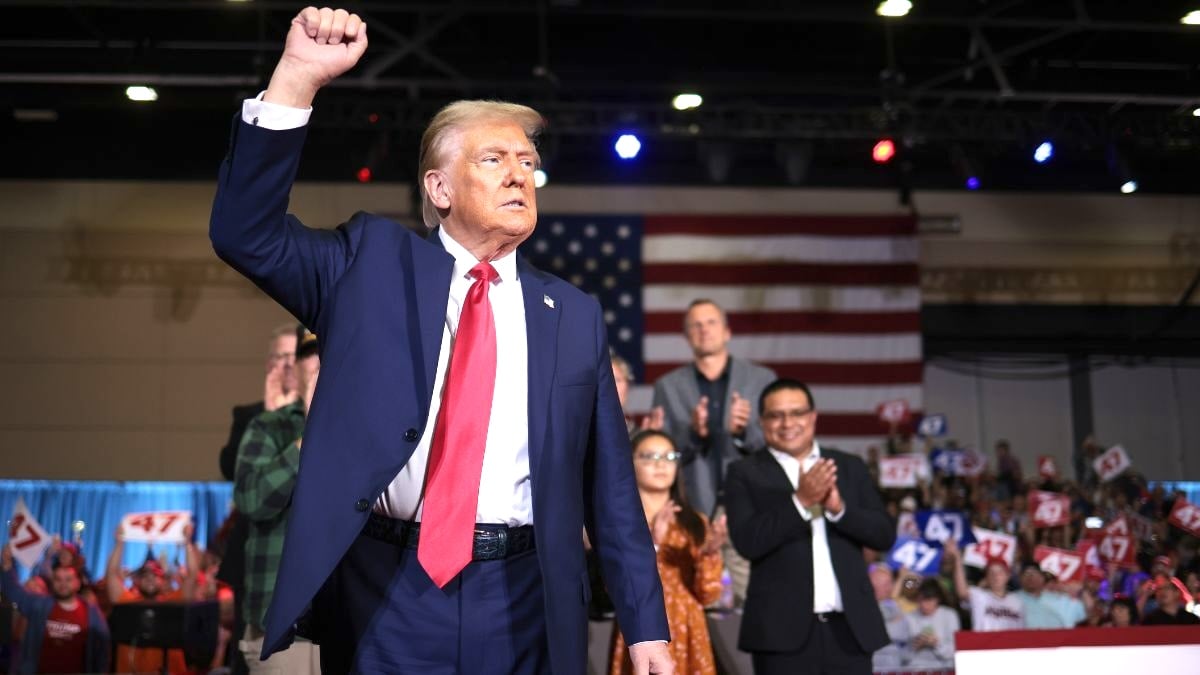 Donald Trump raising his fist at a rally with wrinkled-AF pants