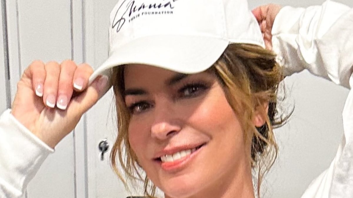 Shania Twain smiling wearing a white baseball cap