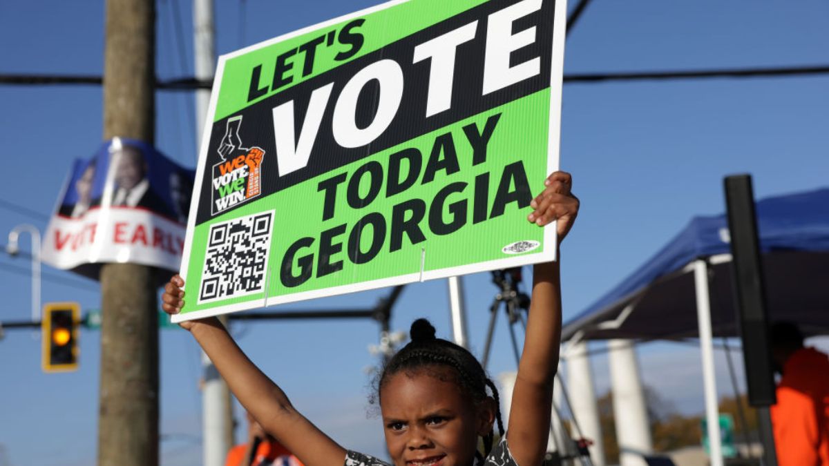 ATLANTA, GEORGIA - NOVEMBER 29: Local resident Reniya Weekes holds a sign to encourage people to vote early outside a polling station on November 29, 2022 in Atlanta, Georgia. Early voting has started in select Georgia counties for a special runoff election days after the Georgia Supreme Court rejected an emergency request from Republicans to block counties from offering early voting. (Photo by Alex Wong/Getty Images)