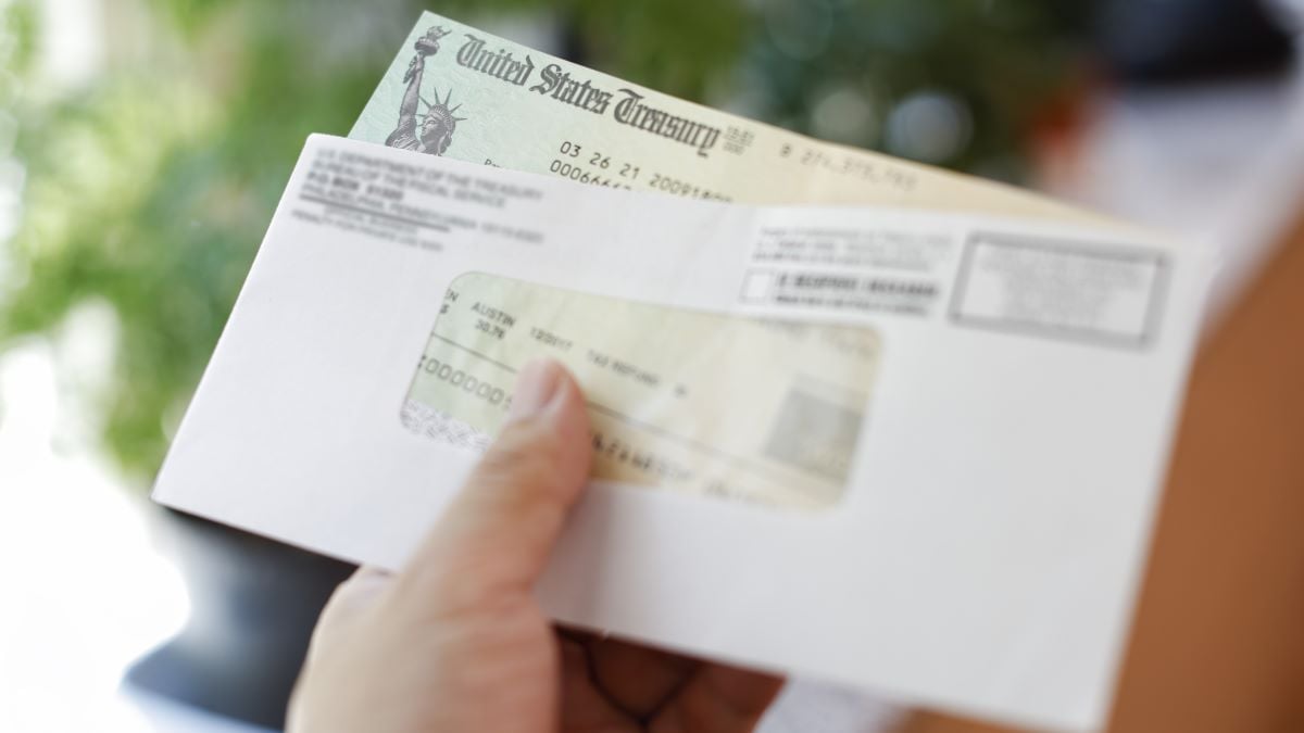 Man receives a tax refund check from the government; Indoor background