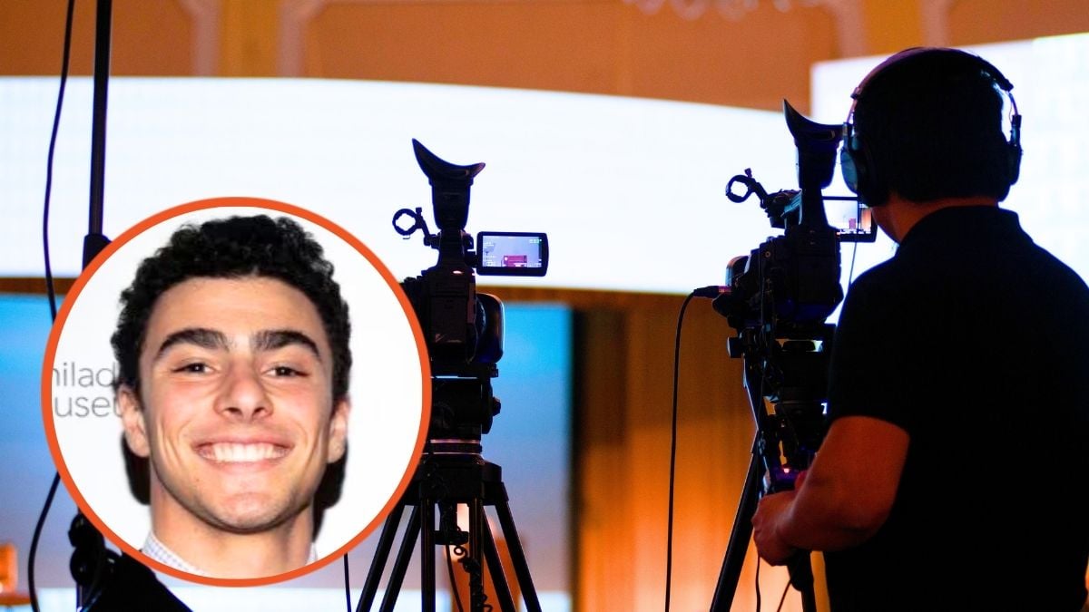 Luigi Mangione and an image of a camera man with two cameras frames his shot for the presentation about to take place on the stage. He is somewhat silhouetted and is wearing headphones.