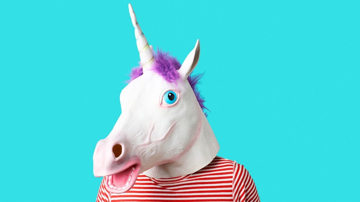 Man wearing a unicorn mask and a red and white striped t-shirt on a blue background with some blank space around him