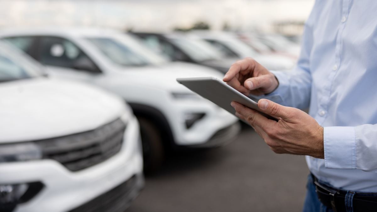 Close-up on a car salesperson using a tablet computer at the car dealership