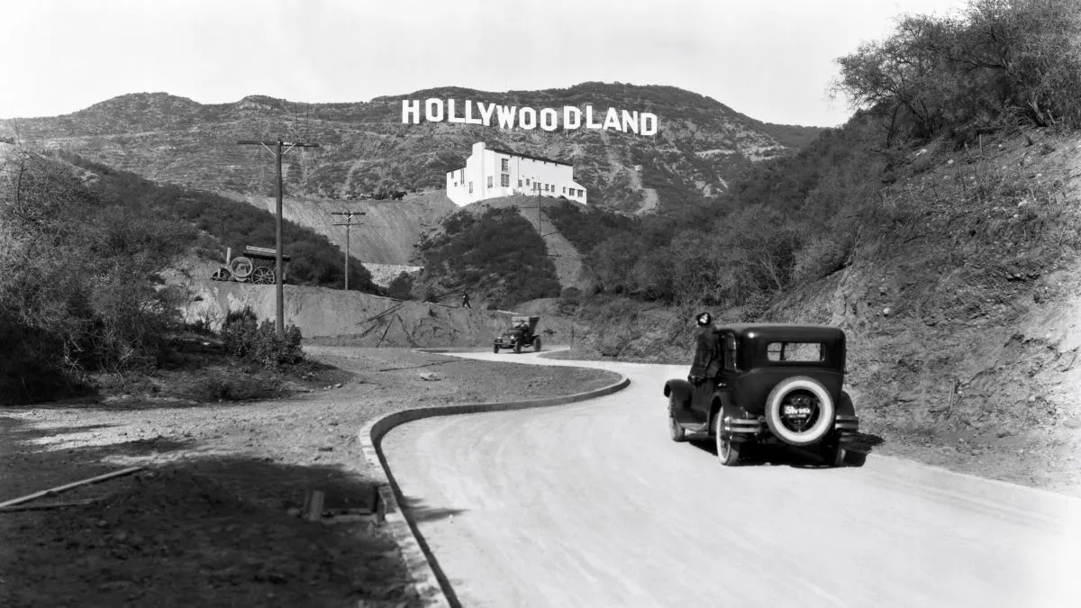 A sign advertises the opening of the Hollywoodland housing development in the hills on Mulholland Drive overlooking Los Angeles, Hollywood, Los Angeles, California, circa 1924. The white building below the sign is the Kanst Art Gallery, which opened on April 1, 1924. (Photo by Underwood Archives/Getty Images)