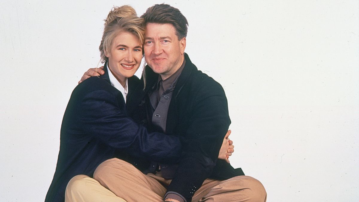 Portrait of American actress Laura Dern and film director David Lynch as they embrace against a white background, 1990. 