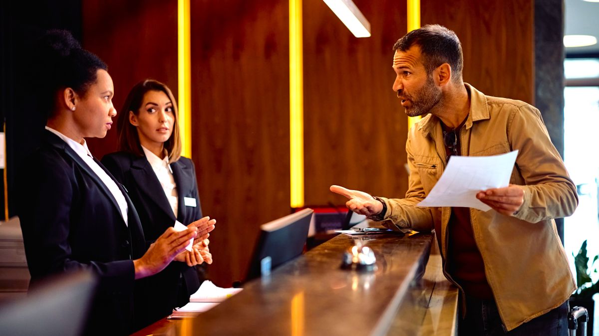 Angry guest discussing with managers while complaining about the bill after a hotel stay.