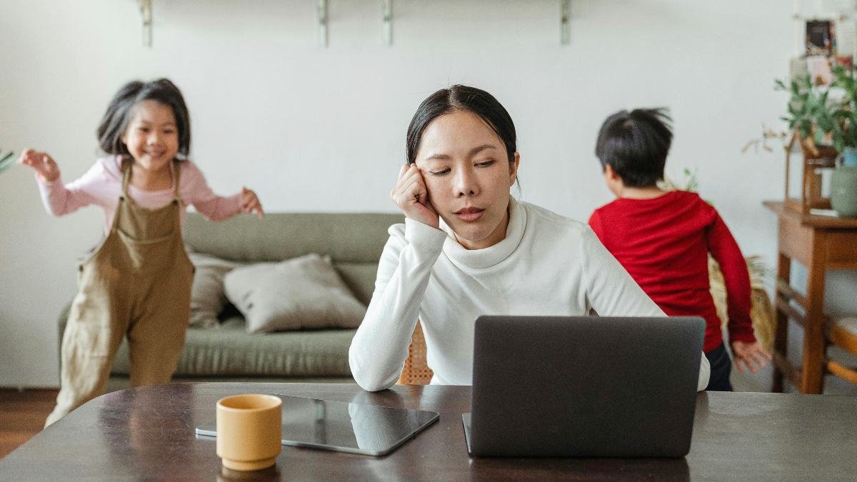Woman on a laptop with kids playing around