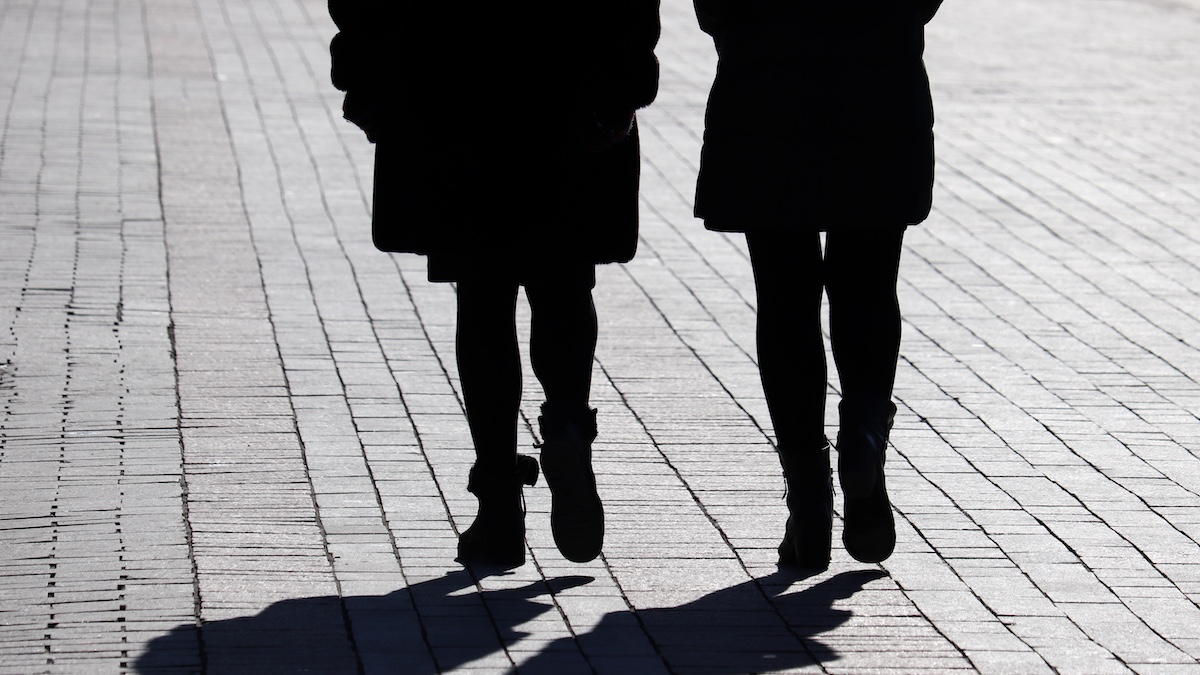Silhouettes and shadows of two women walking down the street