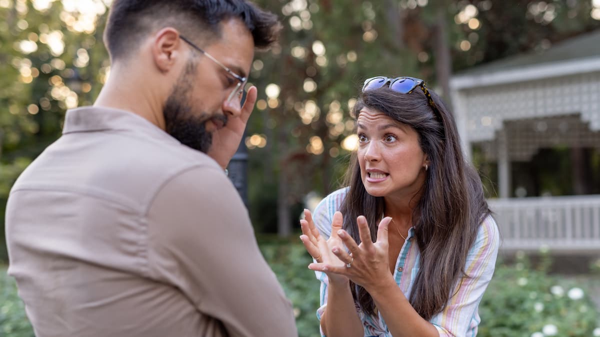 Man listens as woman gestures in intense conversation outdoors. - stock photo