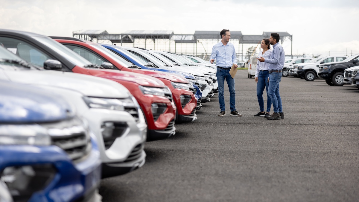 Salesman showing cars to a couple at the dealership