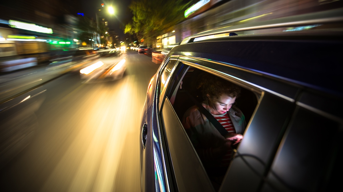 A woman sits in the back of a car via Getty Images, halbergman