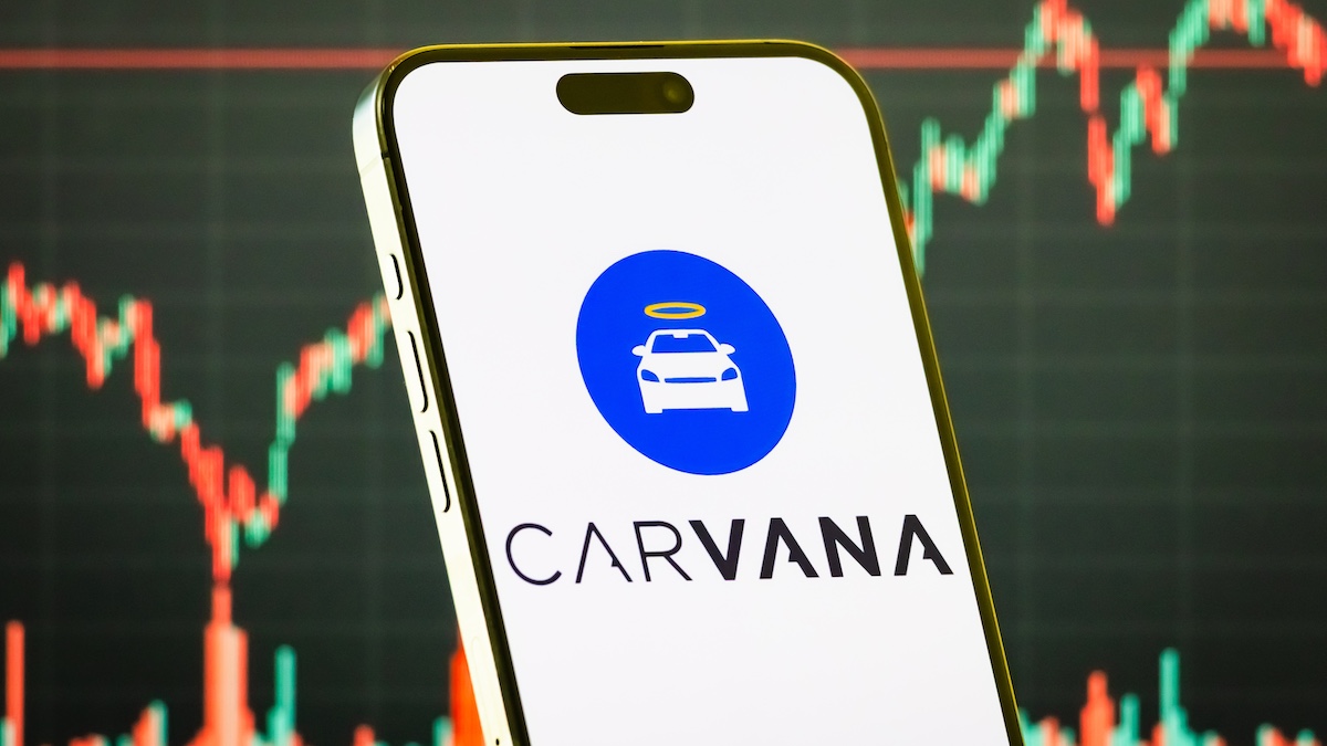 CHONGQING, CHINA - JULY 28: In this photo illustration, a smartphone displays the logo of Carvana Co. (NYSE: CVNA), an American e-commerce company that sells used cars through an online platform, in front of a screen showing the company’s latest stock market chart on July 28, 2025 in Chongqing, China.