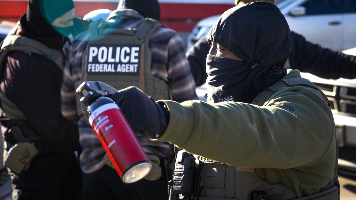 A federal immigration agent threatens photojournalists with pepper spray as they document the agents taking a man off the street and placing him in custody on January 14, 2026 in Minneapolis, Minnesota. The Trump administration has sent aa reported more than 2,000 federal agents into the area, with more on the way, as they make a push to arrest undocumented immigrants in the region. (Photo by Scott Olson/Getty Images)