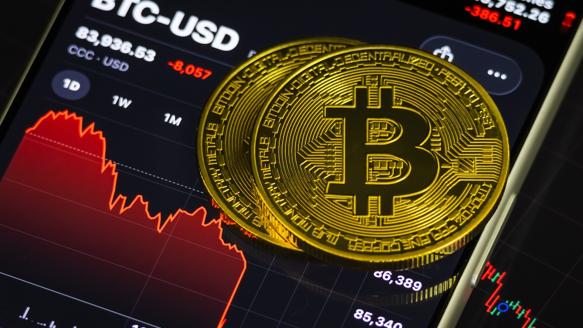 CHONGQING, CHINA – NOVEMBER 21: In this photo illustration, two gold-colored Bitcoin tokens are placed on a smartphone screen displaying a sharply declining BTC-USD price chart on November 21, 2025, in Chongqing, China. Bitcoin recently fell below the mid-US$80,000 range as renewed market volatility, macroeconomic uncertainty, and sustained outflows from crypto investment products pressured digital-asset valuations.