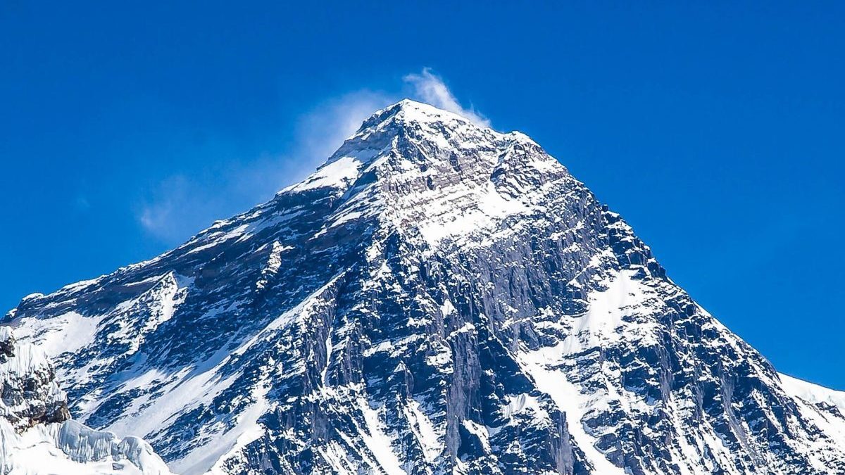 Breathtaking view of Mount Everest with a clear blue sky backdrop, showcasing its snow-capped peak.